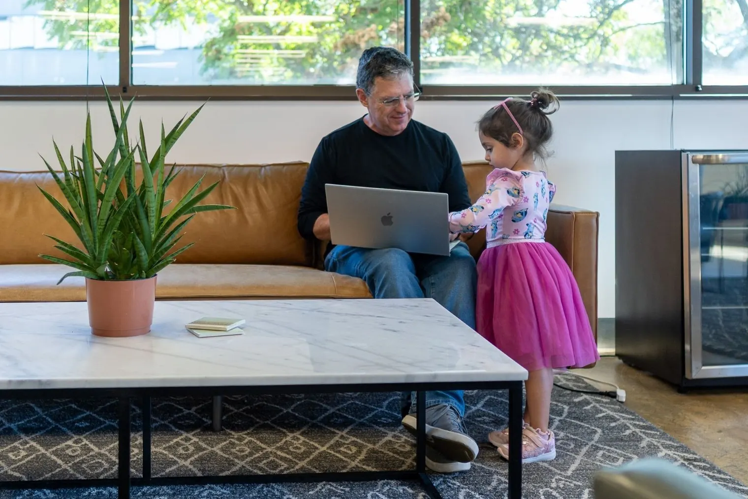 Will Montague on the office couch, reviewing a laptop with a young visitor
